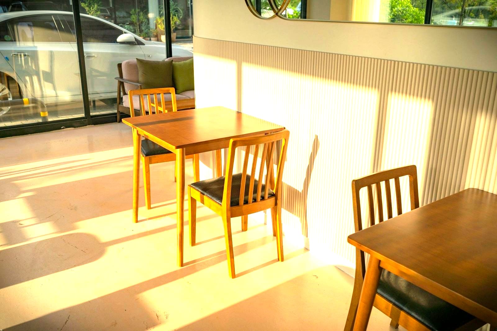 A small table and two chairs in low afternoon sun by the front window
